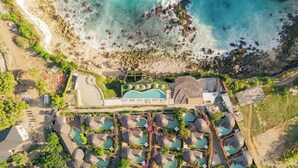 Vue aérienne d’un complexe hôtelier doté de plusieurs piscines, d’une piscine centrale et d’une zone de plage.