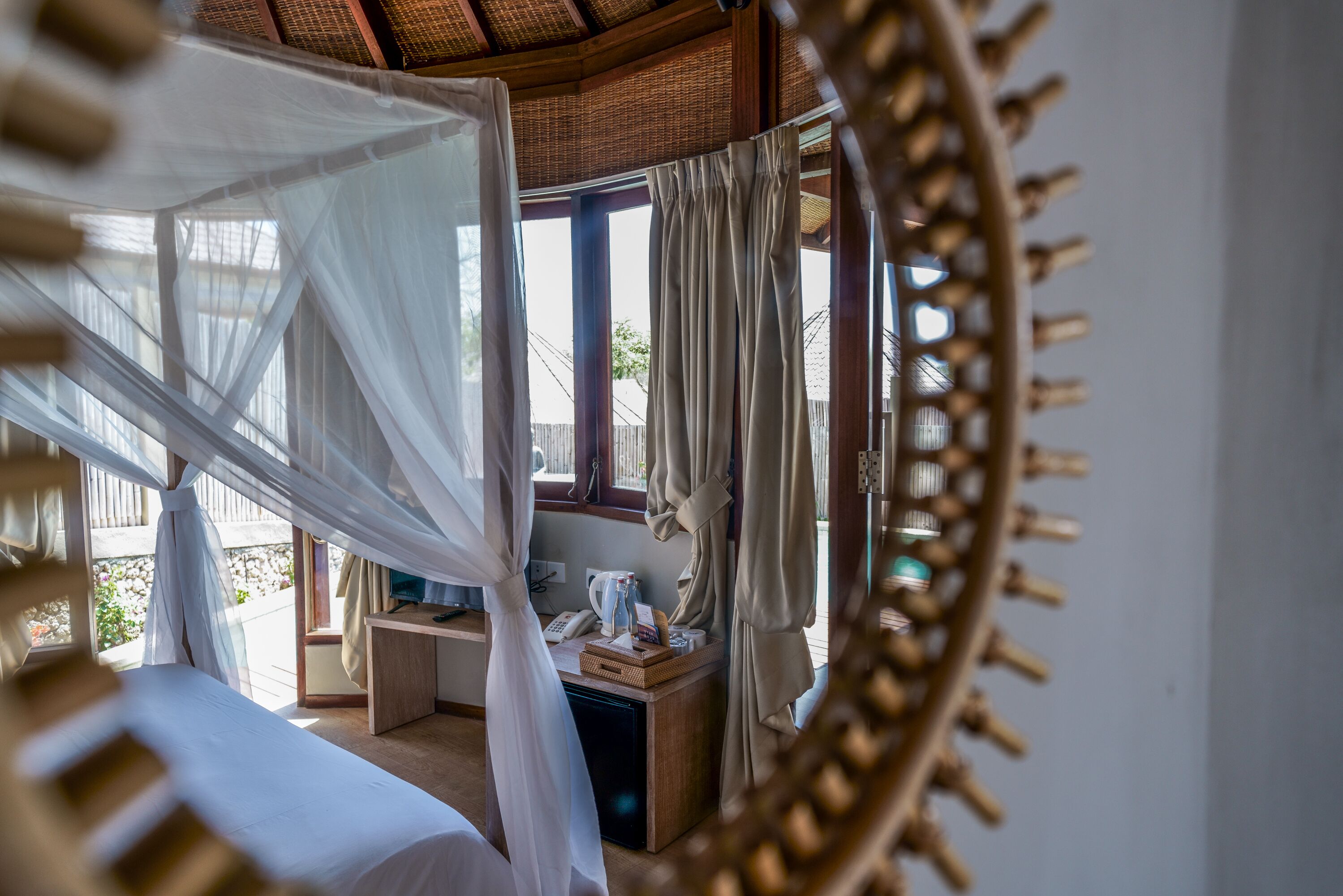 A bedroom with a bed, a desk, and a window with curtains.