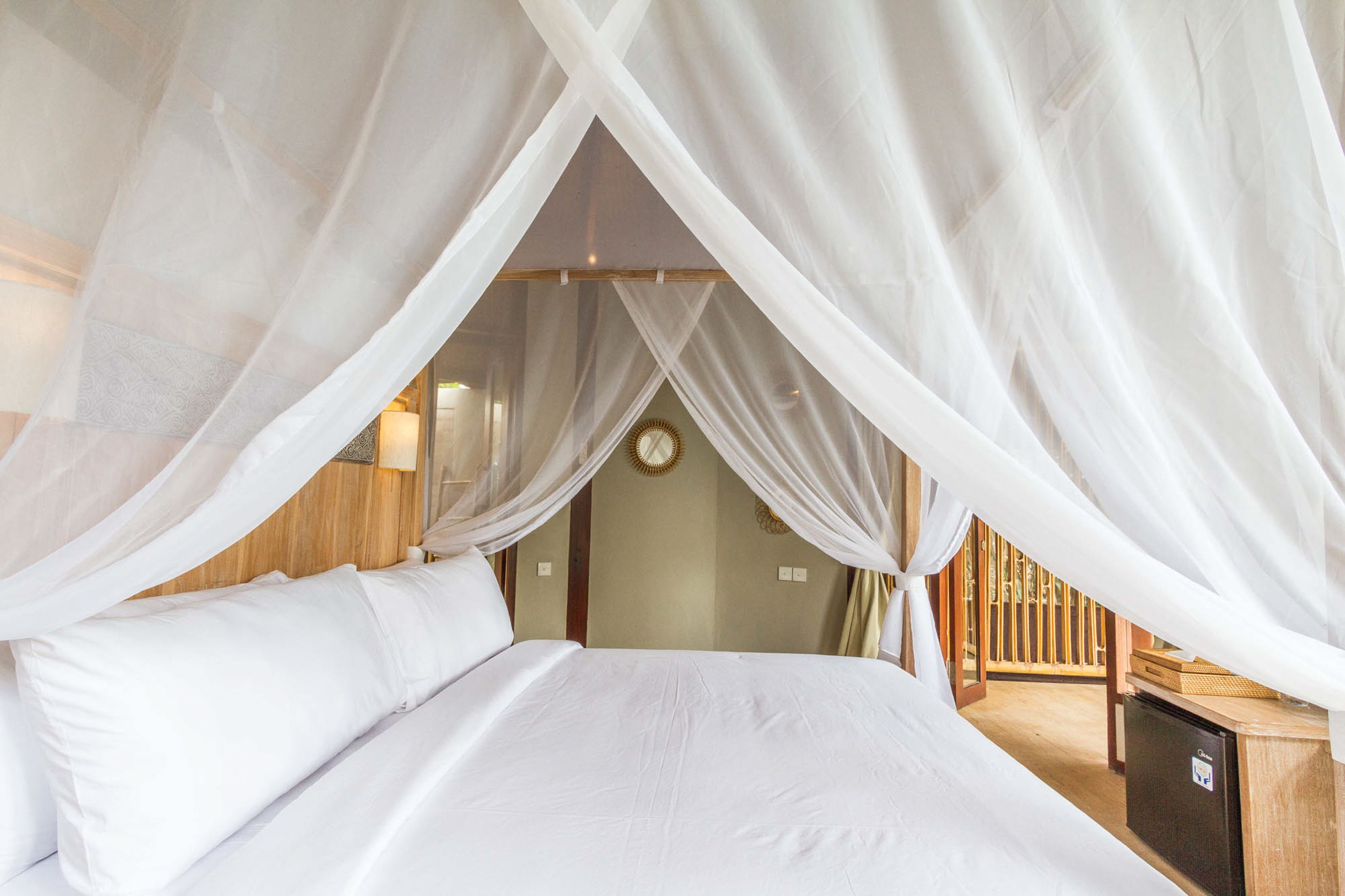 A bedroom with a canopy bed, wooden walls, and a small desk with a lamp.
