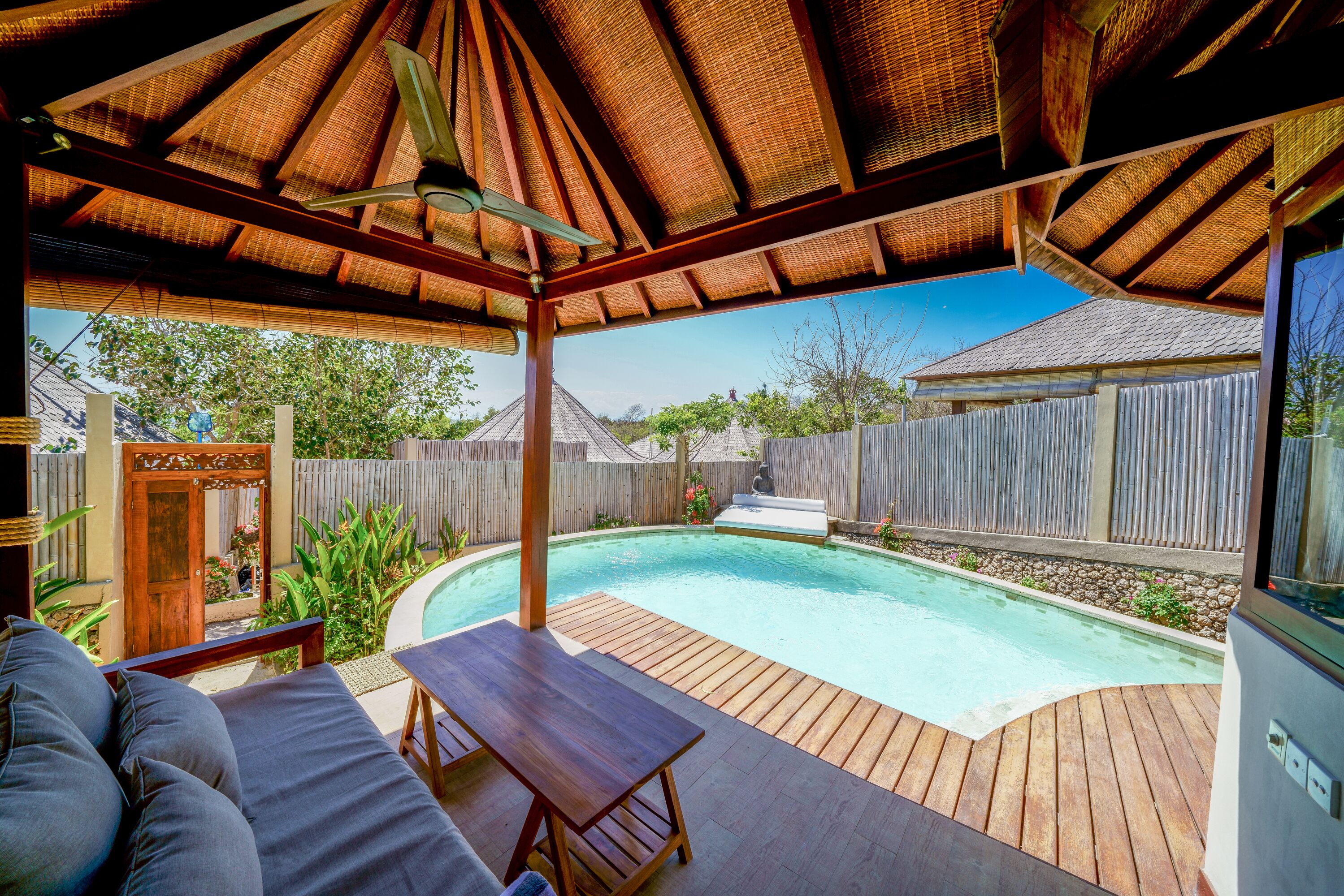 A covered outdoor area with a pool, wooden deck, and seating.