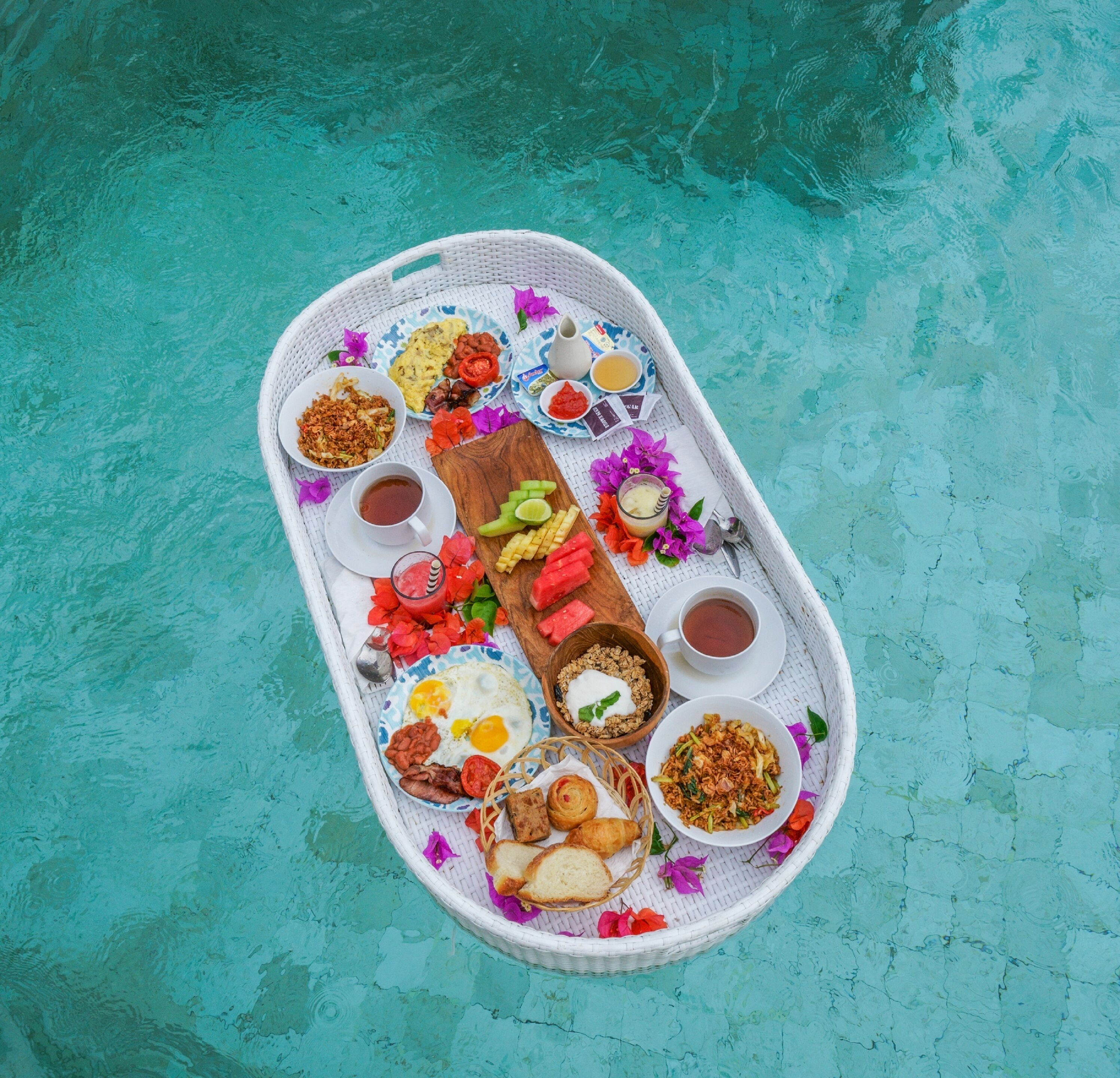 Bandeja de alimentos que incluye huevos, pan y diferentes condimentos, colocada sobre una piscina.