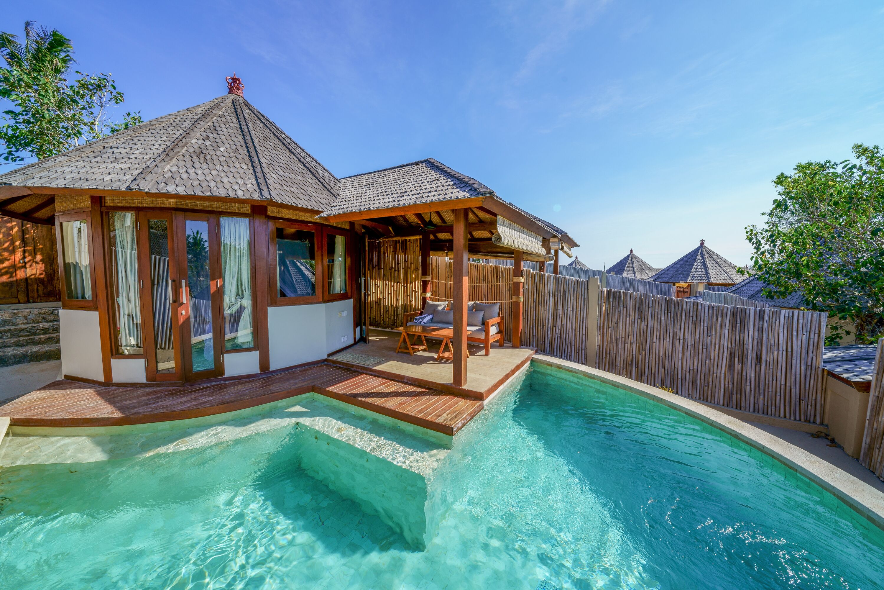 A poolside area with a wooden deck, a covered seating area, and a view of the pool.