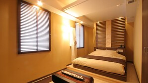 A hotel room with a bed, a bench, and a small table with decorative items. - Hotel Rplus - Adults only (Yachiyo)