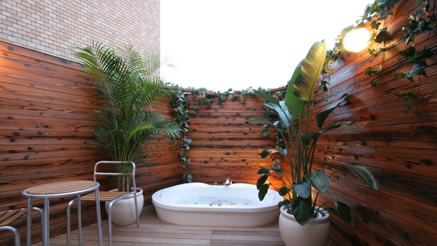 A wooden deck with a hot tub, two metal chairs, and potted plants. - Hotel Rplus - Adults only (Yachiyo)