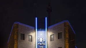 A hotel with a prominent vertical sign featuring the name 'Hotel Rplus' and a modern architectural design with illuminated accents. - Hotel Rplus - Adults only (Yachiyo)