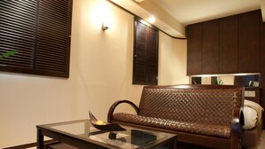 A modern living room with a glass-top coffee table, a brown woven sofa, and dark wooden cabinets. - Hotel Rplus - Adults only (Yachiyo)