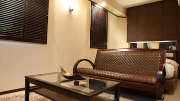 A modern living room with a glass-top coffee table, a brown woven sofa, and dark wooden cabinets.