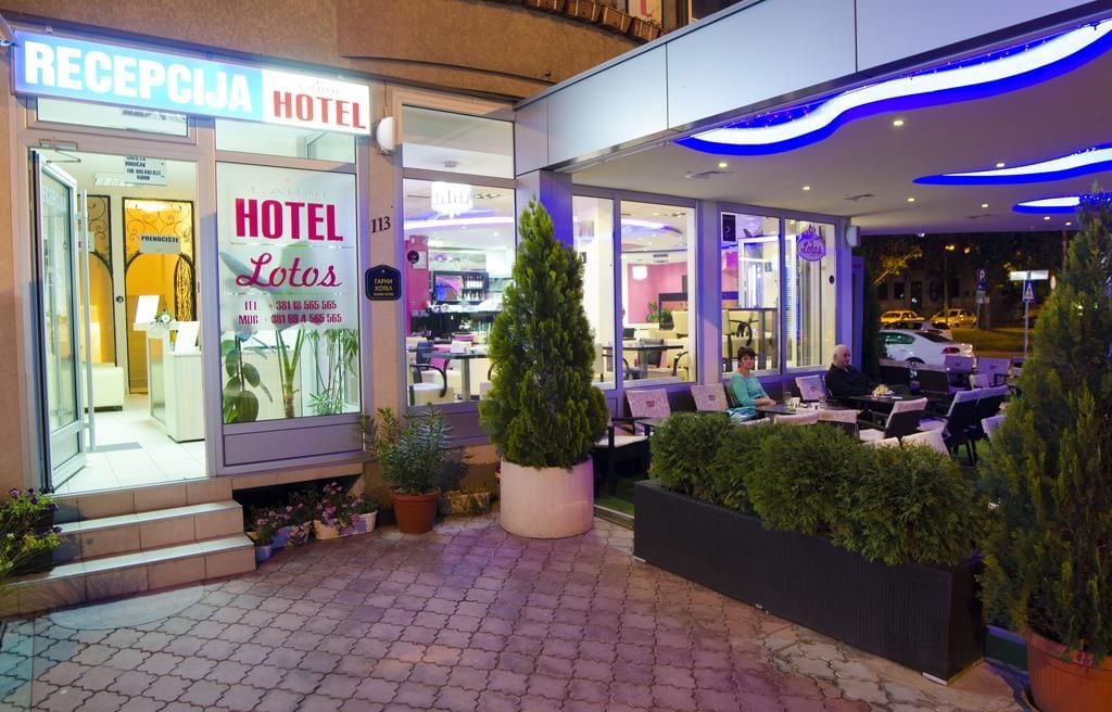 A hotel entrance with a reception area, indoor seating, and a visible staircase leading to the entrance.