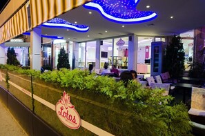 A hotel exterior with a seating area, a sign for 'Lotus', and a 'Hotel' sign. - Garni Hotel Lotos (Niš)