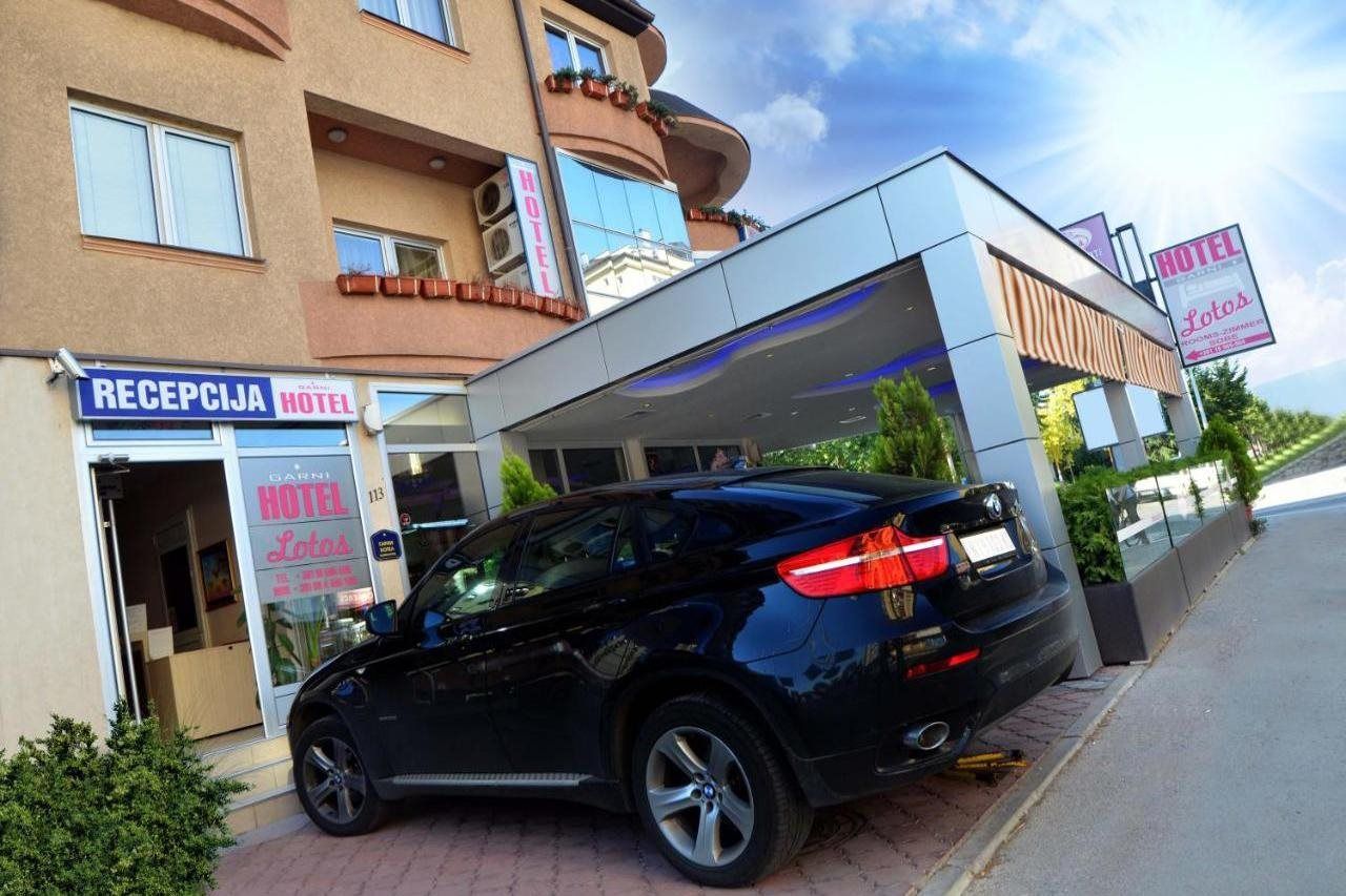 A hotel with a reception area, a black car parked in front, and a clear sky.
