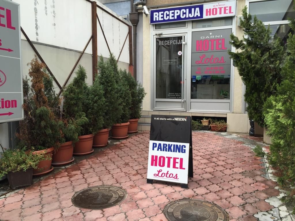 Entrada de un hotel con un letrero que dice 'RECEPCIA HOTEL' y un cartel de estacionamiento.
