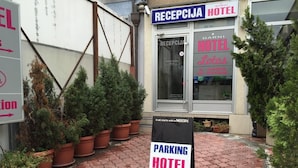 L’entrée d’un hôtel, avec une enseigne indiquant « HÔTEL RECEPCIA » et un panneau de signalisation pour le stationnement.