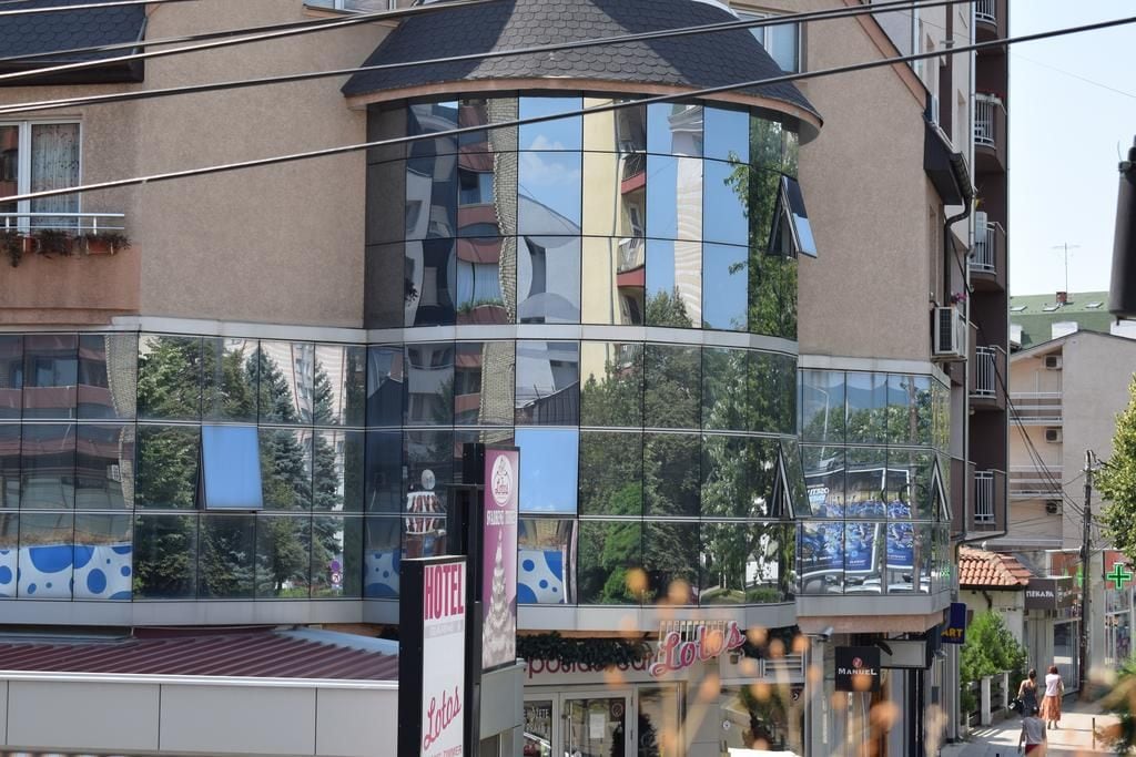A multi-story hotel with a curved glass facade, balconies, and a visible ground floor with shops.