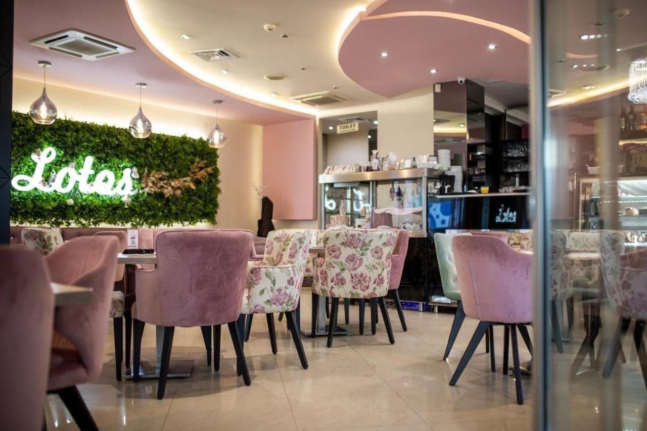 A cafe interior with pink chairs, a neon sign, and a green wall.
