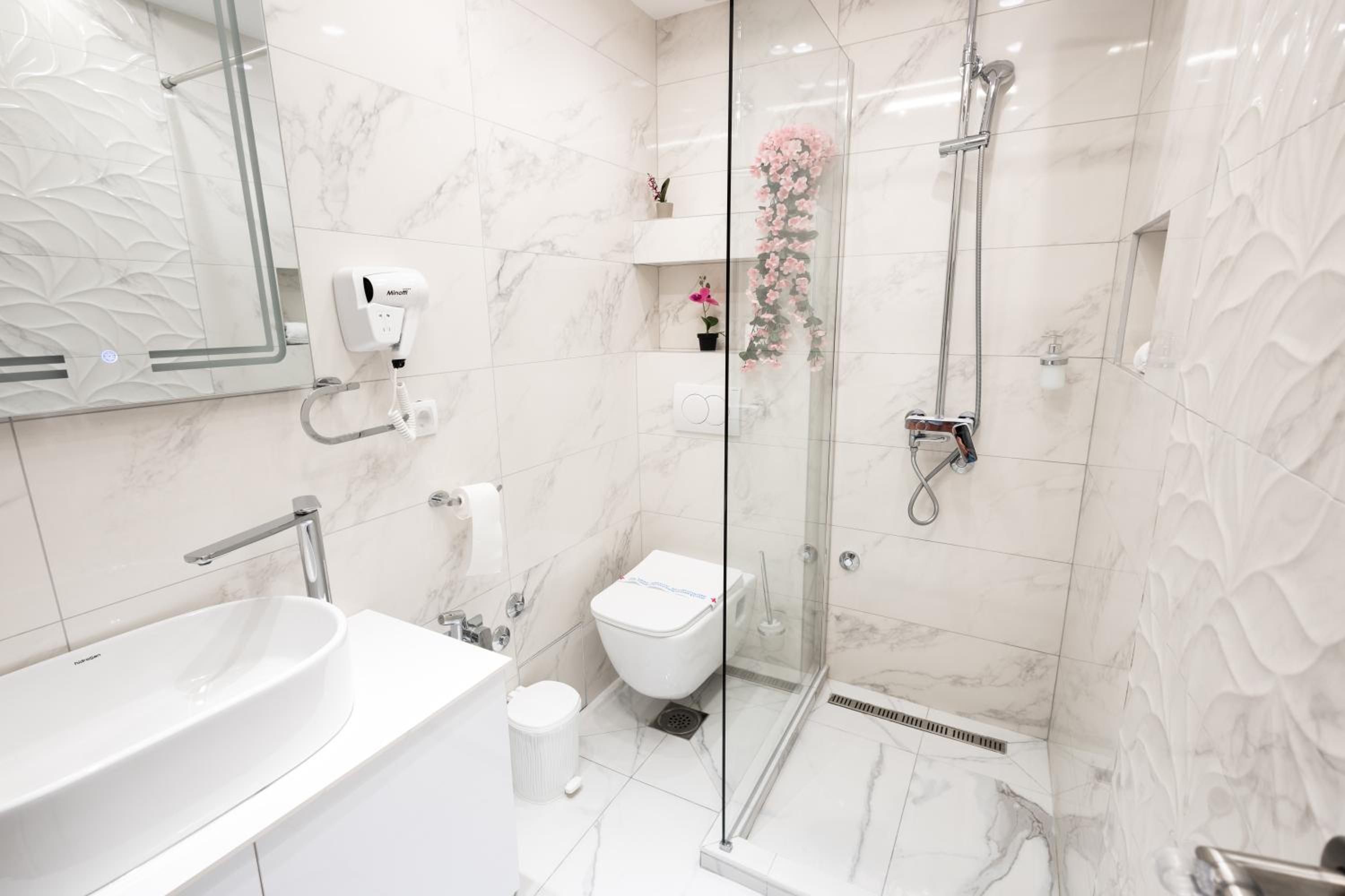 Um banheiro moderno com uma pia grande e branca, um chuveiro com parede de vidro e um vaso sanitário.