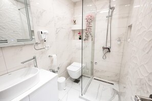 Ein modernes Badezimmer mit einem großen weißen Waschbecken, einer Glaskabine für die Dusche und einer Toilette.