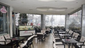 Un restaurant avec un présentoir de glaces, des chaises noires et blanches et de grandes fenêtres.