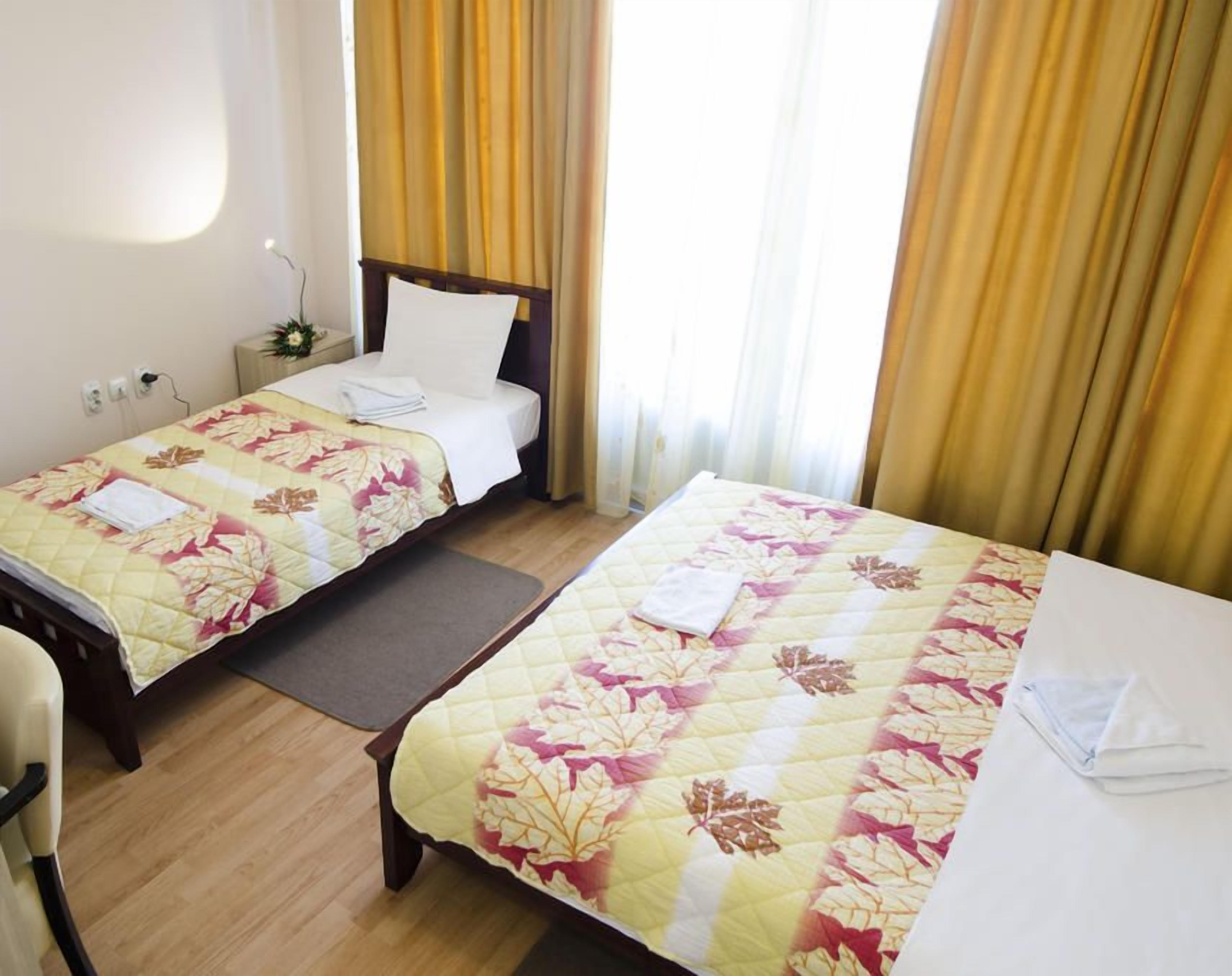 A hotel room with two beds, a desk with a computer, and a TV.