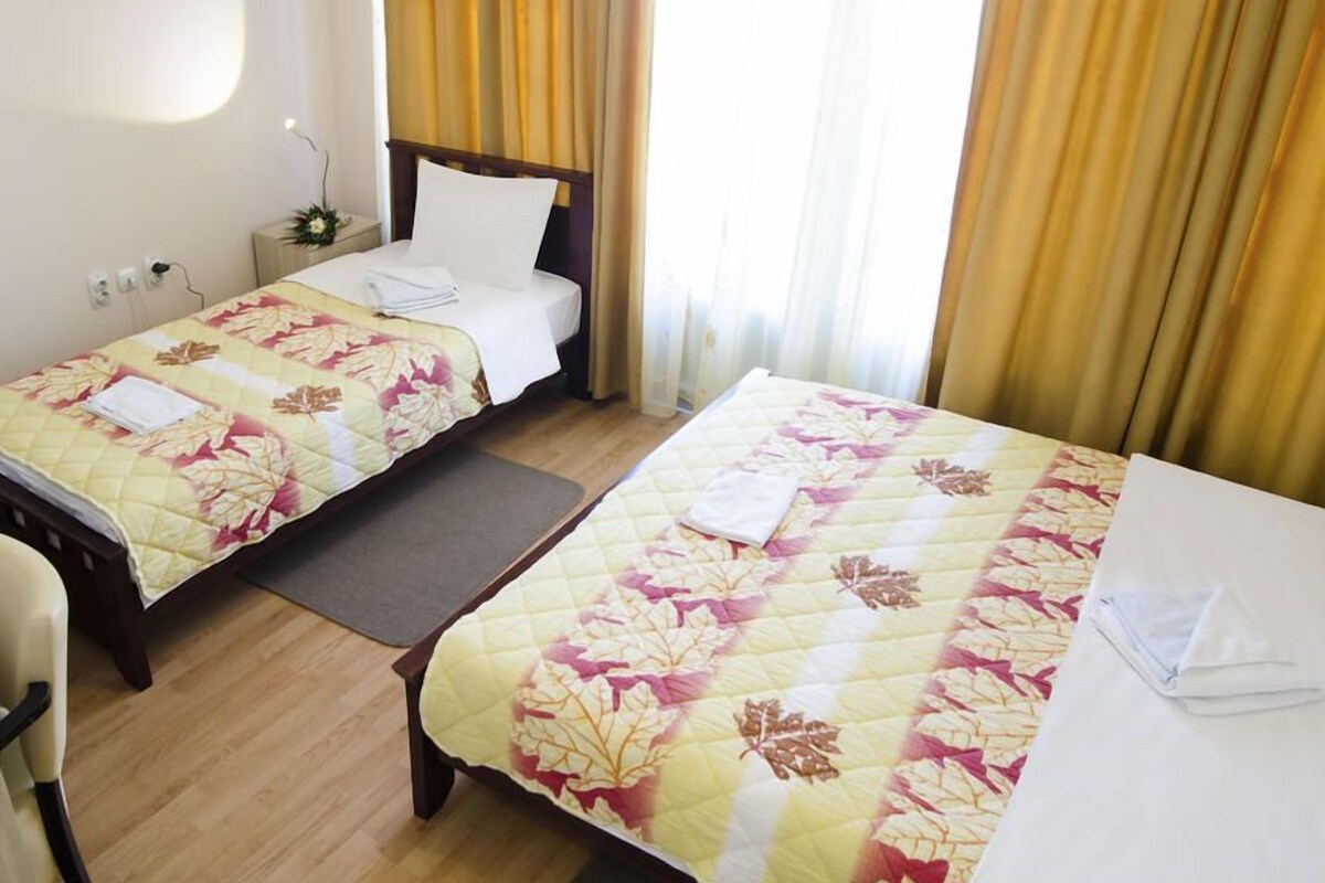 Une chambre d’hôtel avec deux lits, un bureau avec un ordinateur et une télévision.