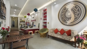 A modern living room with a sofa, chairs, a dining table, and a kitchen area. - D'annam Hostel Hanoi (Hanoi)