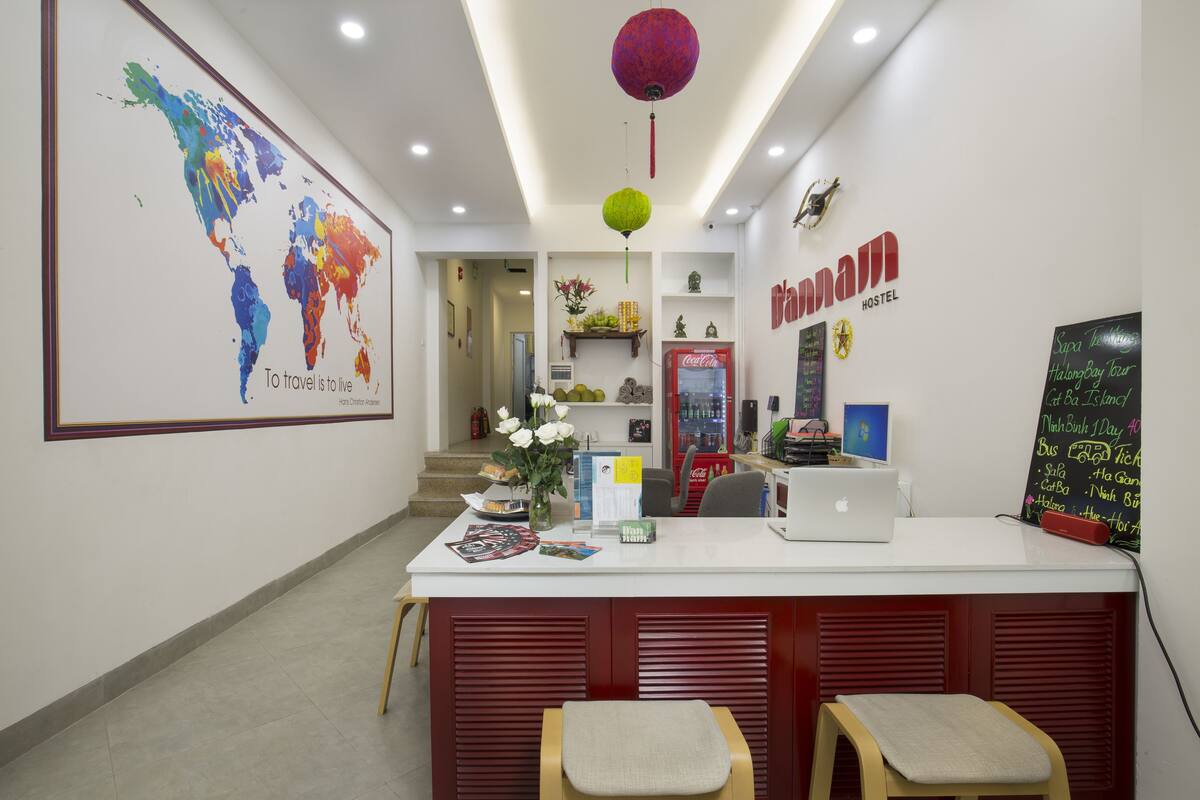 A reception desk with a laptop, a Coca-Cola refrigerator, and a world map.