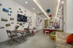 A modern hotel room with a dining area, a sofa, and a TV mounted on the wall. - D'annam Hostel Hanoi (Hanoi)