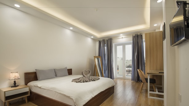 A modern bedroom with a large bed, bedside table, and a desk area. - D'annam Hostel Hanoi (Hanoi)