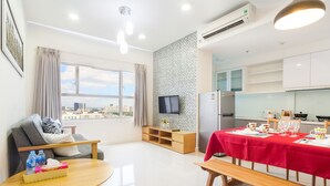 A modern living room with a sofa, a dining table set for four, a TV, and a city view.