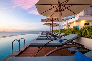 A poolside area with lounge chairs and umbrellas, overlooking a body of water. - TMS Hotel Da Nang Beach (Da Nang)