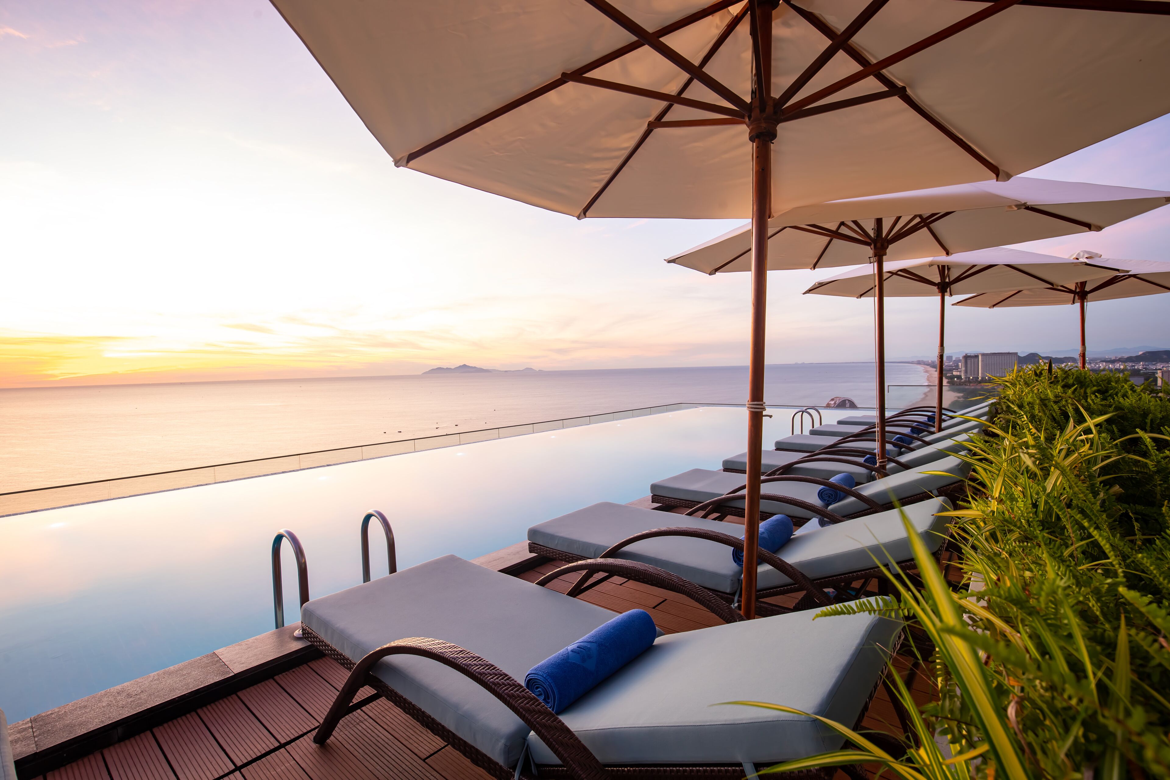 Un espace aménagé au bord de la piscine, avec des chaises longues et des parasols, donnant sur une étendue d’eau calme.
