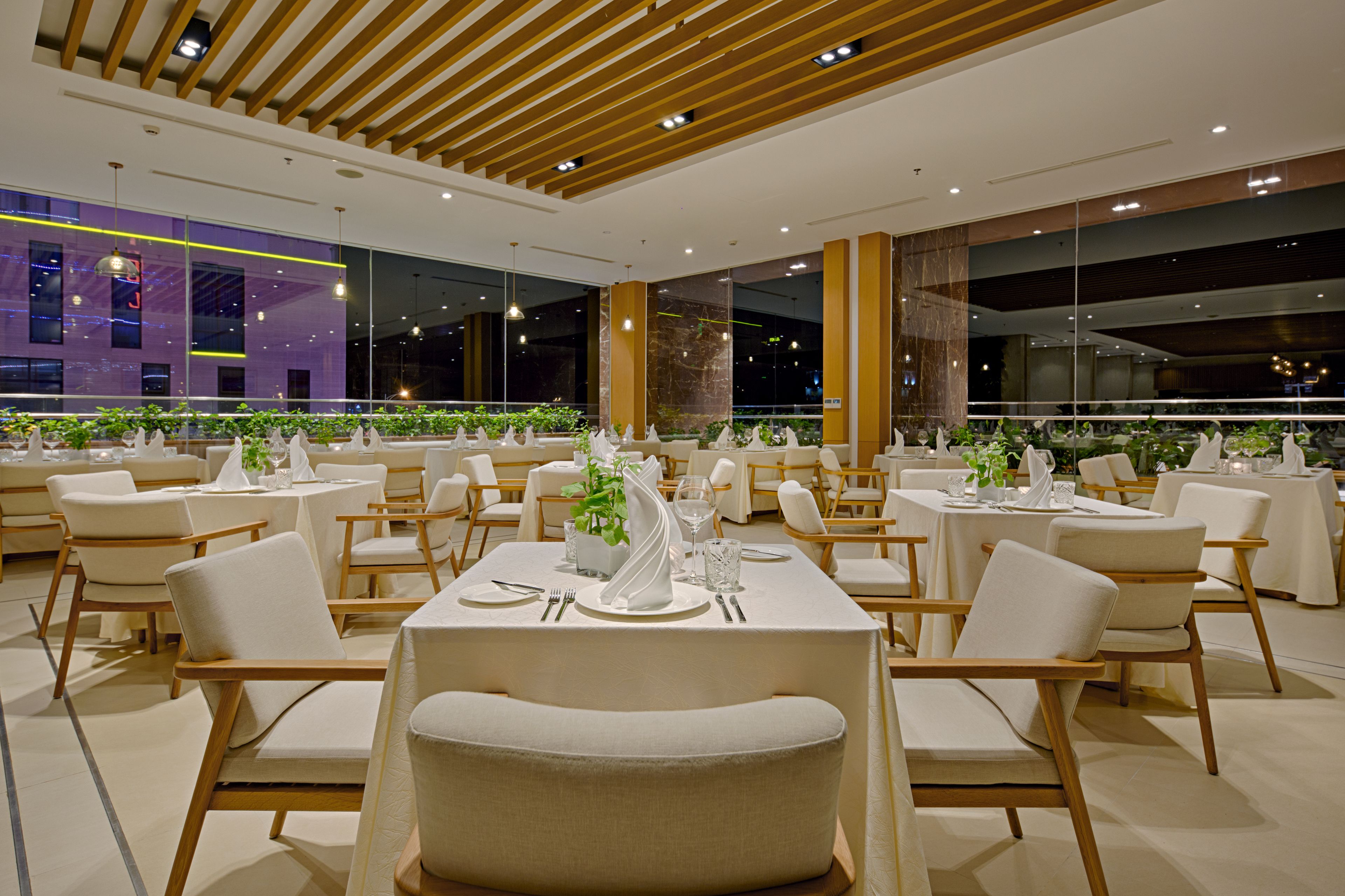 A modern dining area with round tables, white chairs, and a central decorative plant.