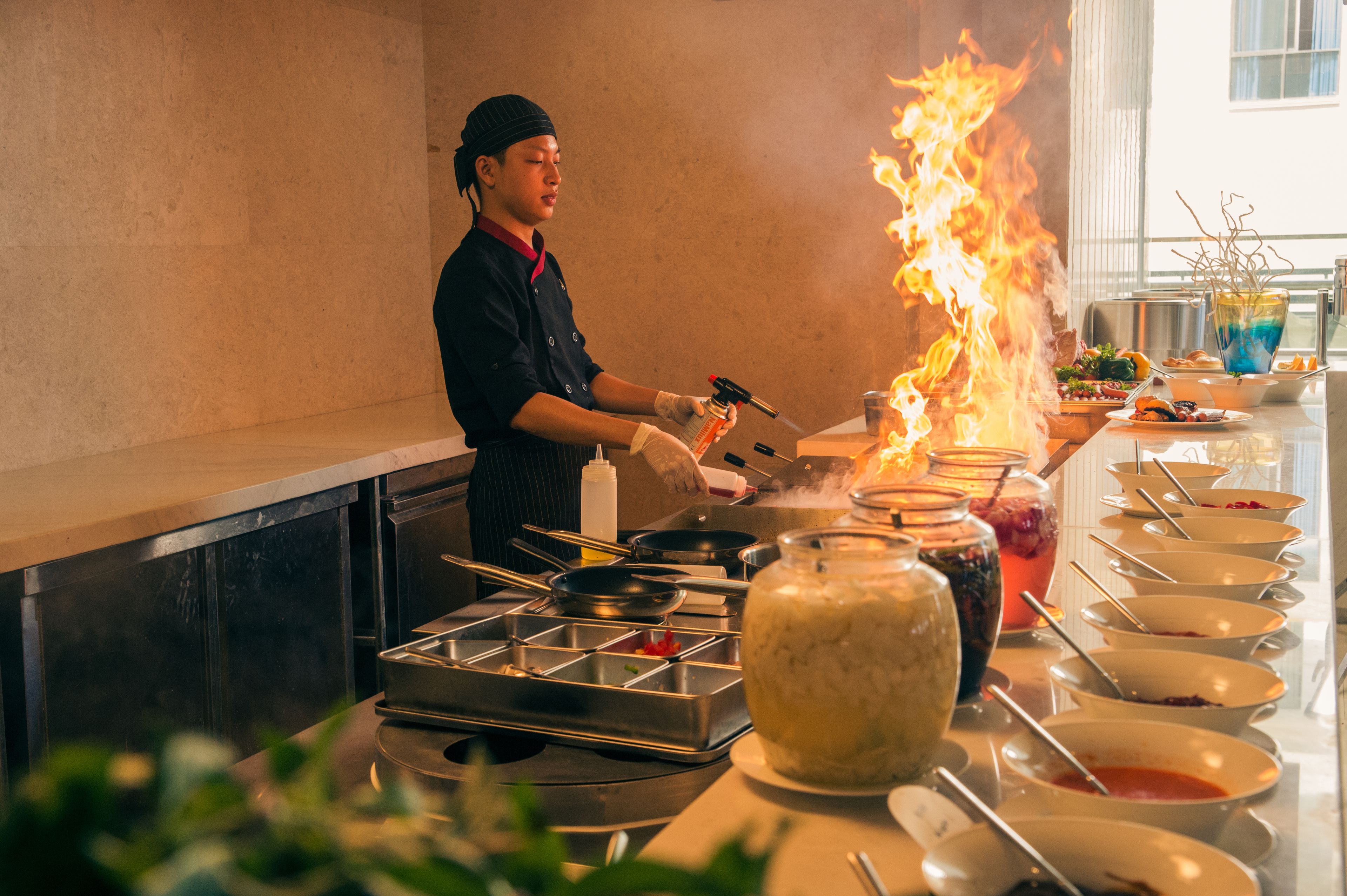 Un chef cuisinant à la flamme sur une cuisinière dans un restaurant.