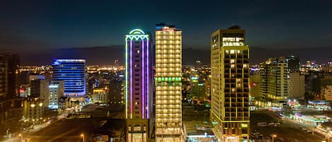 A cityscape at night with illuminated high-rise buildings, including a hotel with a prominent sign.