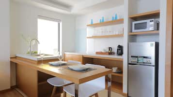 A modern kitchen with a wooden island, white chairs, a built-in microwave, and a refrigerator.