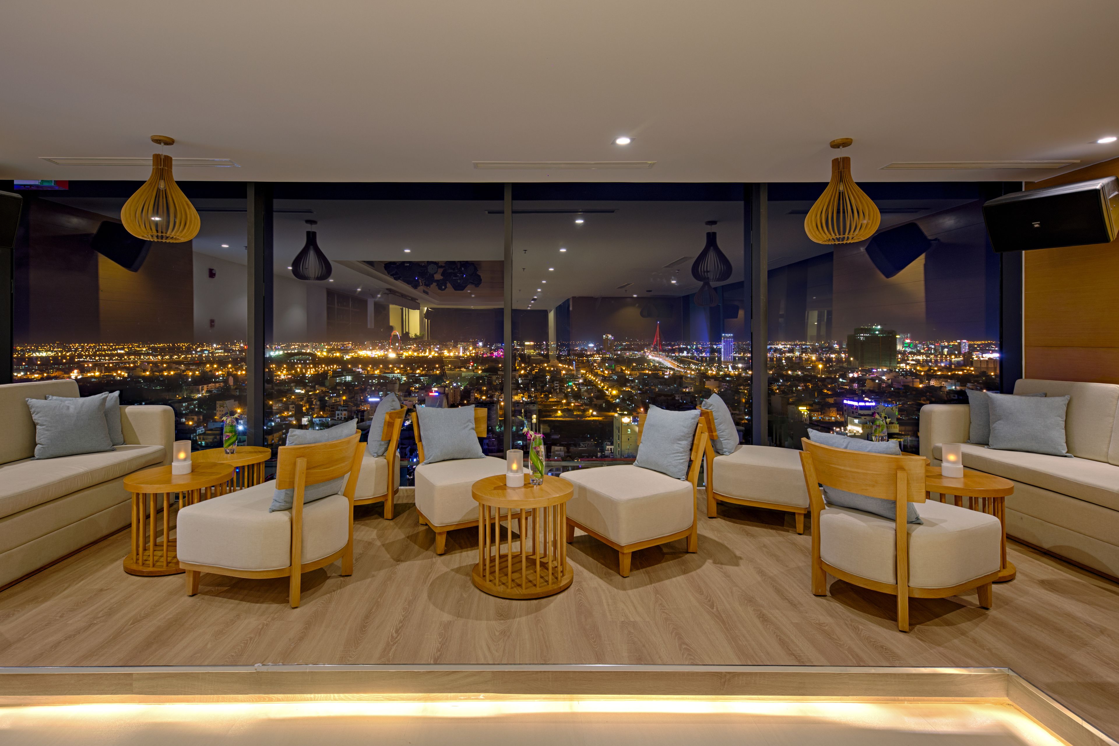 Una sala d'attesa moderna con vista sulla città, con divani, tavolini rotondi e luci a sospensione.