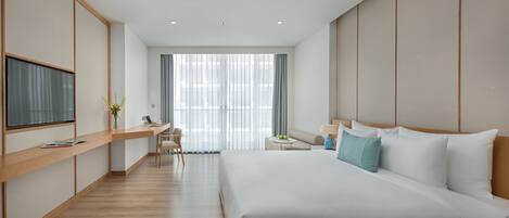 A modern hotel room with a large bed, a desk, and a seating area.