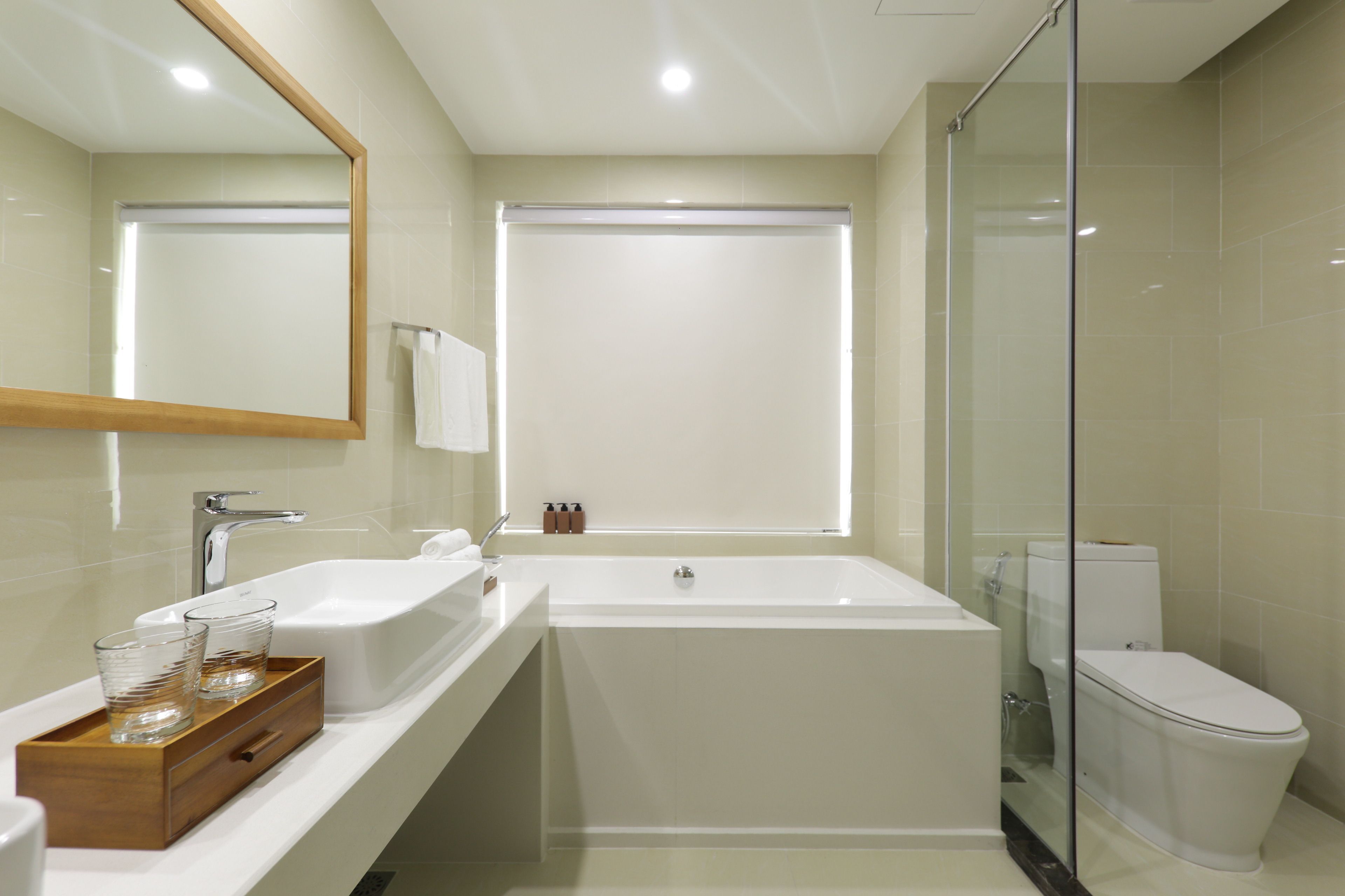 Une salle de bain moderne dotée d’une grande baignoire, de toilettes séparées et d’un espace de douche délimité par des parois en verre.