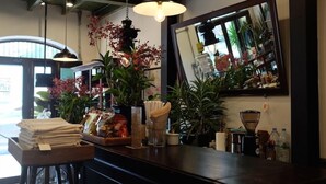 A bar area with a stack of folded napkins, a tray of snacks, and various bottles. There are hanging lights and a large mirror on the wall.