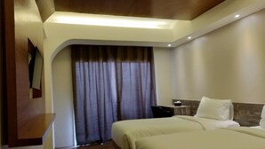A hotel room with two beds, a large window with curtains, a wooden floor, and a modern ceiling design. - Quins Style Resort Belitung (Tanjung Pandan)