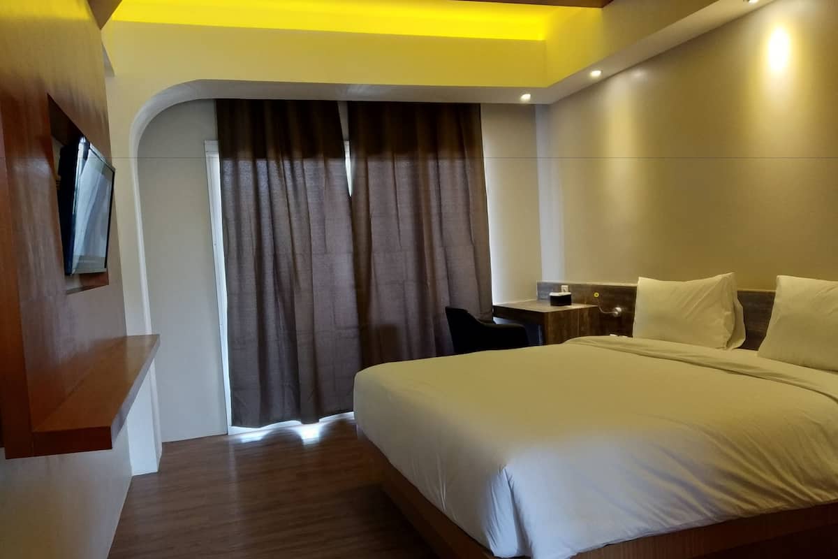 Een moderne hotelkamer met een groot bed, een bureau en een aan de muur bevestigde televisie.