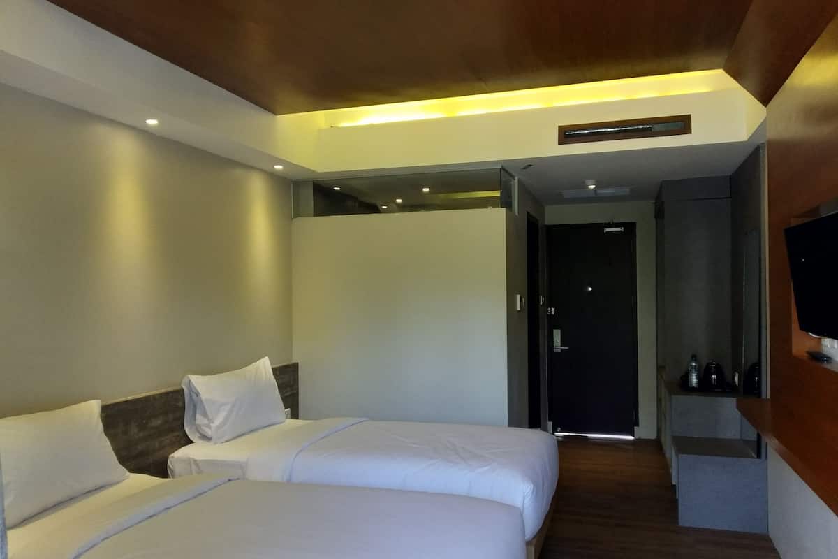 Een hotelkamer met twee bedden, een televisie en een zithoekje.