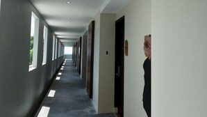 A long, narrow hallway with a tiled floor and white walls. - Quins Style Resort Belitung (Tanjung Pandan)