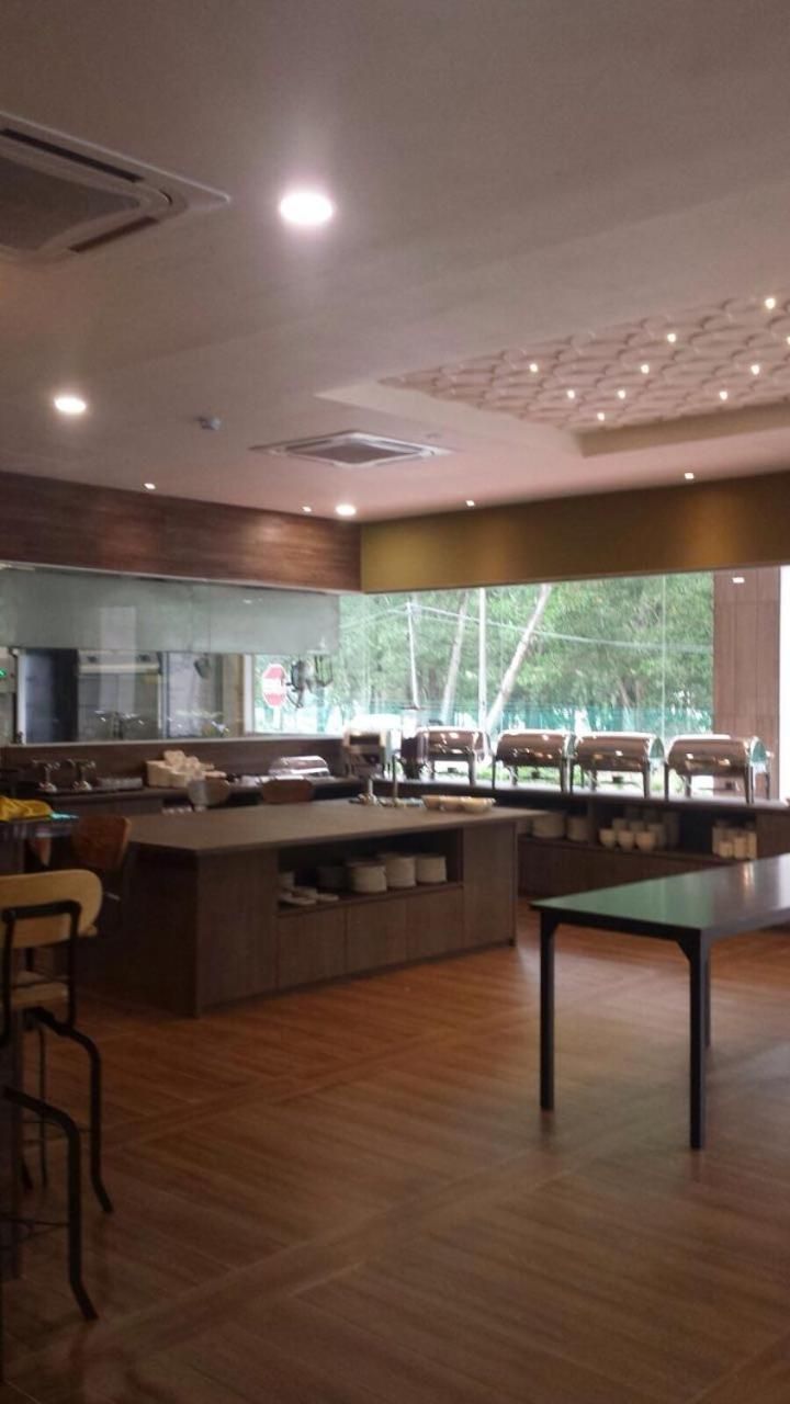A modern kitchen with a central island, bar seating, and a large window providing a view of the outdoors.