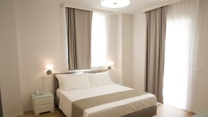 Una habitación de hotel moderna con una cama grande, mesitas de noche y una mesita auxiliar.