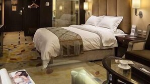 A hotel room with a bed, bedside table, lamp, and a mirror. - Xinchuan Shouzuo Hotel (Mianyang)