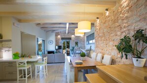Una cucina moderna con mobili bianchi, un tavolo da pranzo in legno e un muro in pietra.