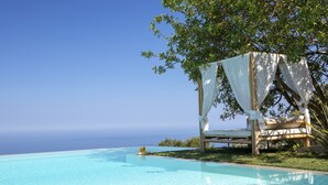 Zona piscina con una panchina in legno e un ombrellone.