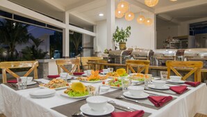 A dining area with multiple tables set for a meal, featuring a variety of dishes and a potted plant. - Palma Resort Phu Quoc, Trademark Collection by Wyndham (Phu Quoc)