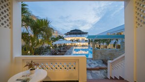 A pool area with lounge chairs and umbrellas, a staircase leading to a building with a dome structure, and a potted plant on a table. - Palma Resort Phu Quoc, Trademark Collection by Wyndham (Phu Quoc)