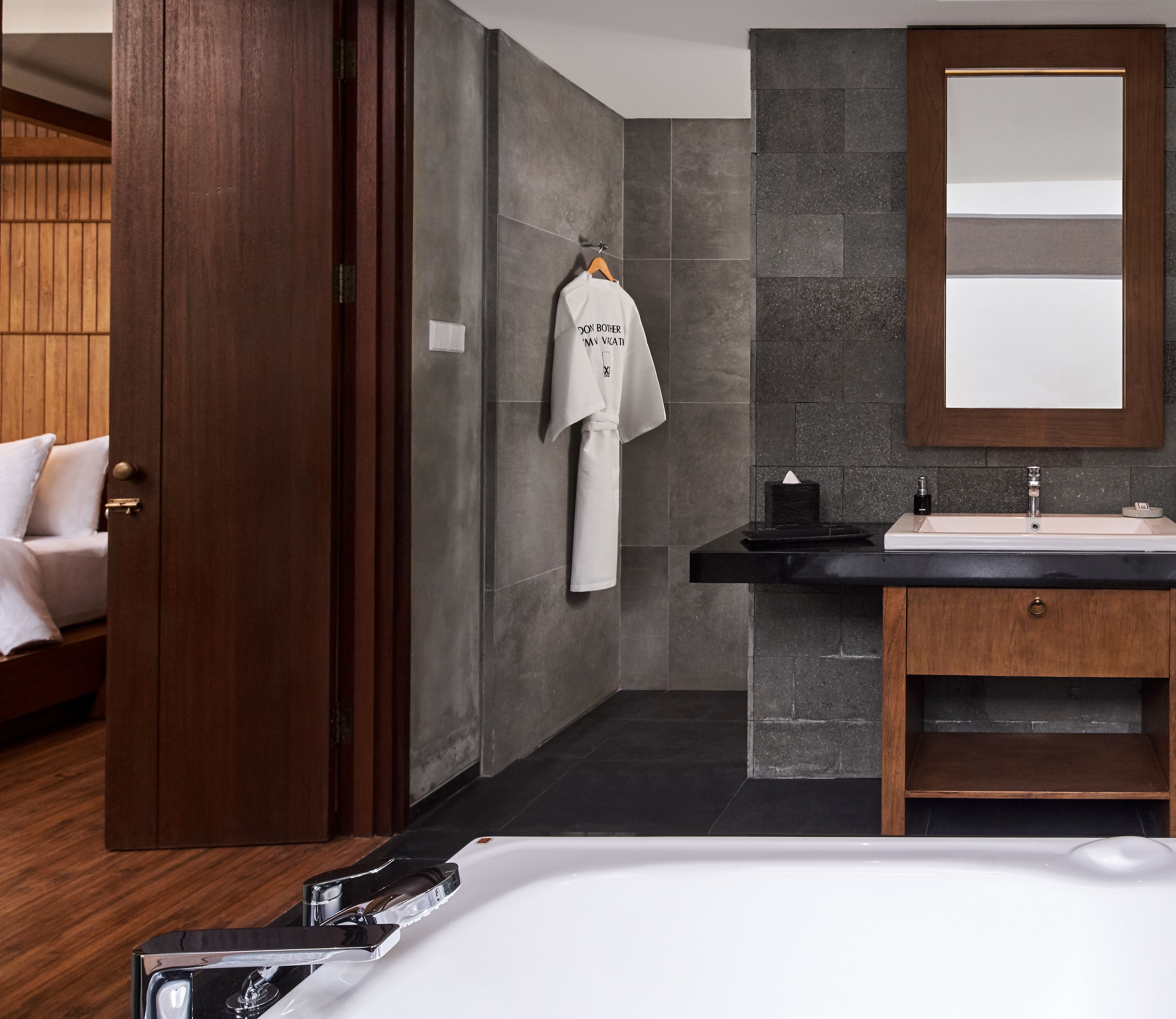 A modern bathroom with a large mirror, a white sink, and a wooden vanity.